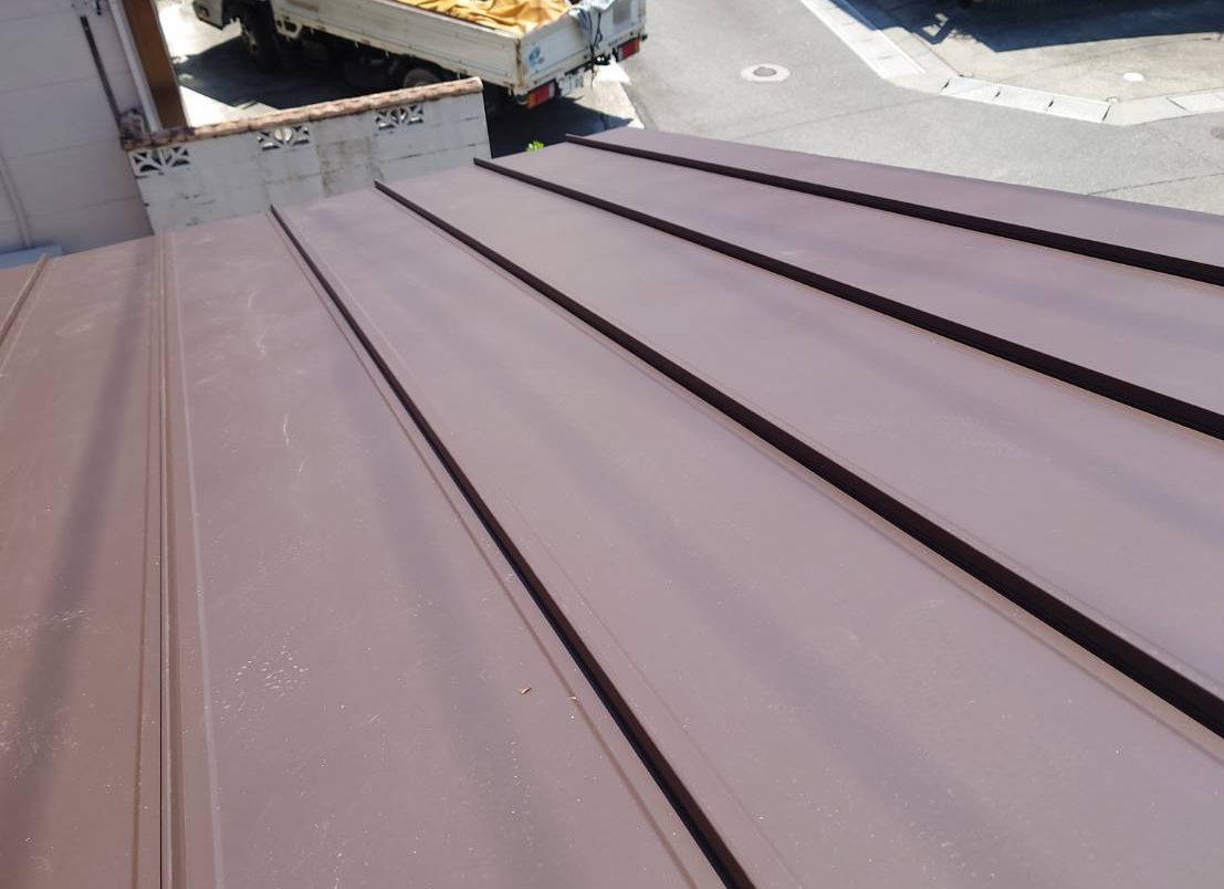 川越町のカラーベスト屋根カバー工法にて施工中、新屋根材タテヒラ板金の敷設
