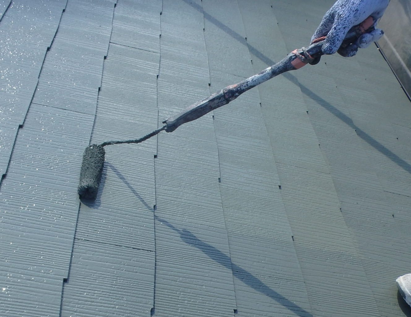 四日市市三滝台にてカラーベスト屋根塗装、上塗り塗装している風景