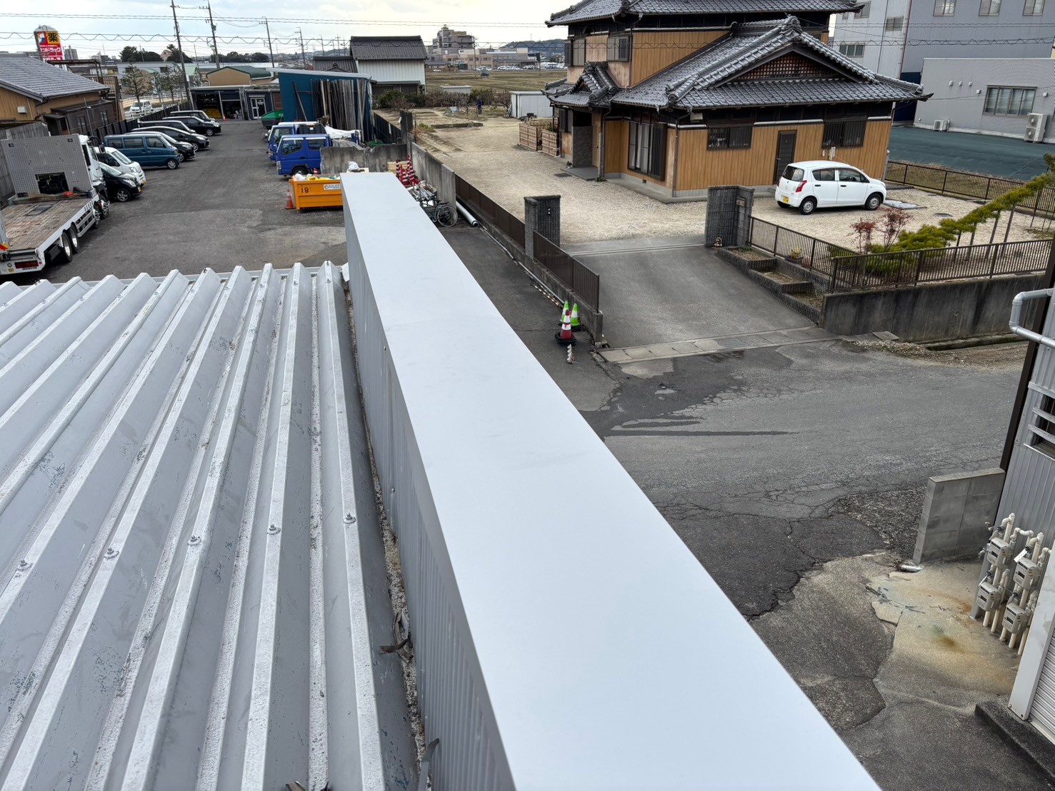 笠木の劣化により雨漏りが発生していた倉庫屋上に、新たに大きめの笠木を被せて雨漏り修理を実施した様子
